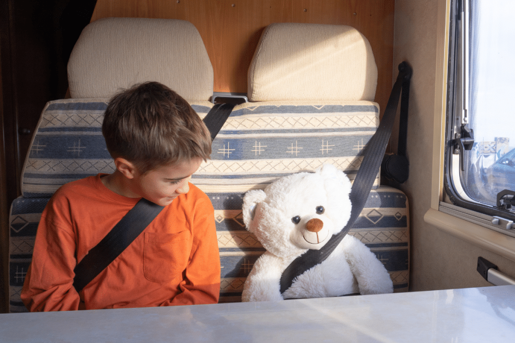 kind met teddybeer in gordel zitplaats camper