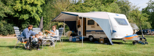 Gezin aan tafel met caravan op de camping